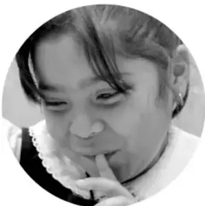 Fotografía en blanco y negro de una niña pensativa con la mano en el mentón.