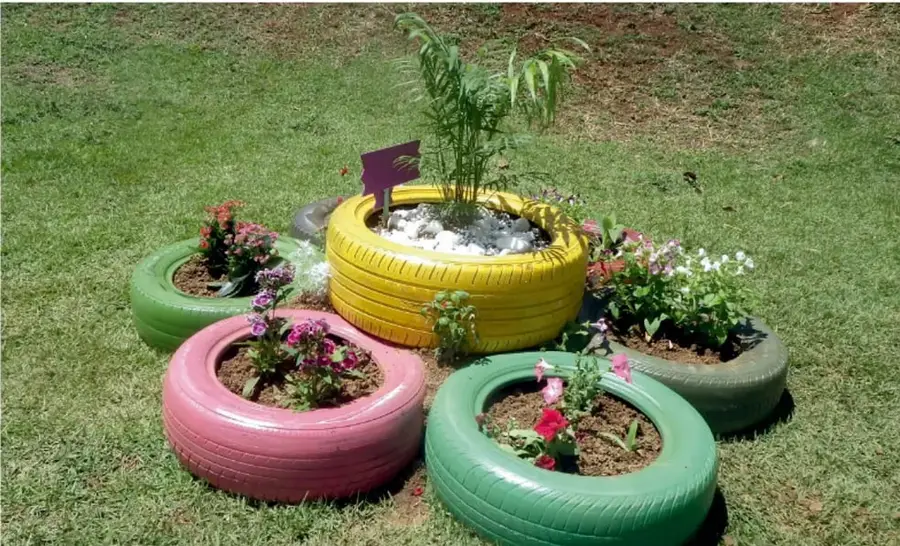 Llantas pintadas de colores usadas como macetas con flores y plantas, ejemplo de reutilización de materiales.
