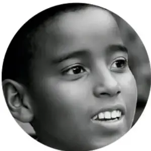 Fotografía en blanco y negro del rostro de un niño mirando hacia arriba, con expresión de asombro o reflexión.