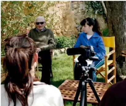 Escena 1: una periodista entrevista a una chef; hay una cámara de video y un camarógrafo en un espacio al aire libre.