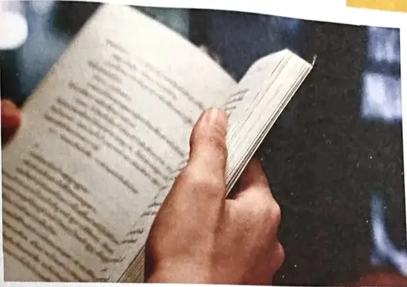 Una persona sostiene y lee un libro abierto. La imagen acompaña la explicación de que el libro participa en el acto de leer.