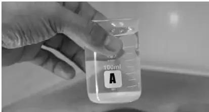 Una mano con guante introduce el vaso A en un congelador; el vaso está rotulado A y contiene 100 mL.