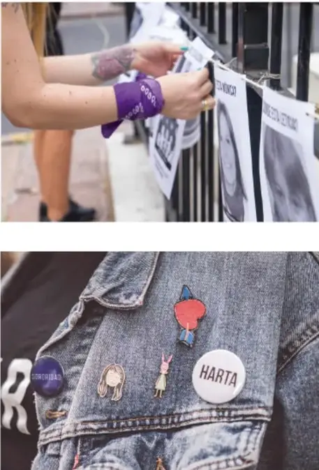 Manos colocan carteles en una reja; una persona lleva una banda morada con la palabra 'sororidad'.