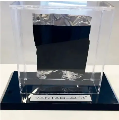 Fotografía de un cubo de vidrio con una placa de Vantablack en su interior, sobre una base negra con la palabra VANTABLACK.