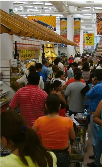 Fotografía de un supermercado lleno de compradores con carritos, ilustrando la sociedad de consumo.