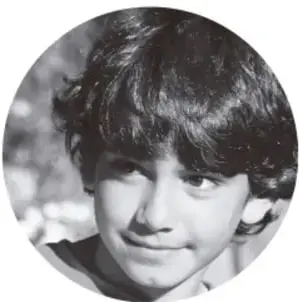 Fotografía en blanco y negro de un niño sonriendo, con cabello oscuro y crespo.
