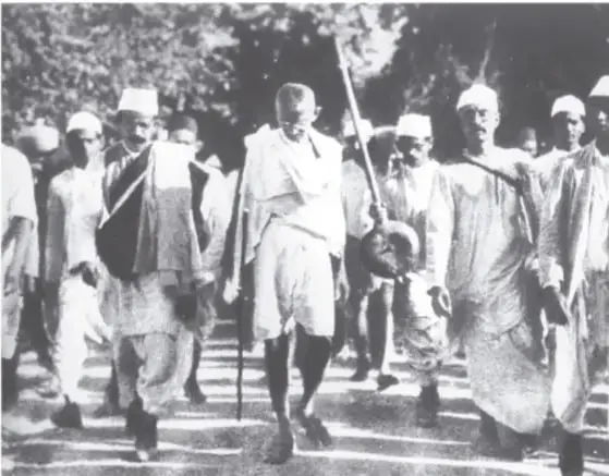 Retrato fotográfico de Mahatma Gandhi joven, con traje y corbata, brazos cruzados.