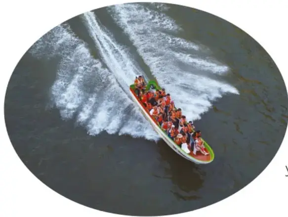 Fotografía vista desde arriba de una lancha de turismo llena de pasajeros que avanza por el río dejando espuma blanca en el agua.