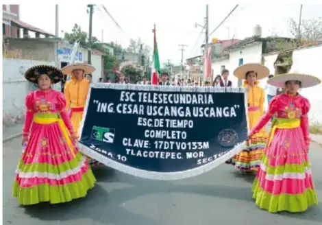 Fotografía de un desfile cívico de la Escuela Telesecundaria 'Ing. César Uscanga Uscanga' (Esc. de Tiempo Completo, Tlacotepec, Morelos), con estudiantes vestidos con trajes típicos portando un estandar escolar.