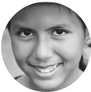 Fotografía en blanco y negro de una niña sonriente, con cabello recogido, mirando a la cámara.