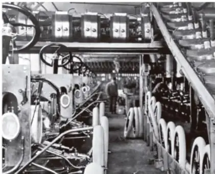 Interior de una fábrica con maquinaria industrial, vinculada a la producción en serie y al urbanismo industrial.