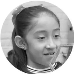 Fotografía en blanco y negro de una niña sonriendo, con una pajilla en la boca, como ejemplo de expresión corporal y emocional.