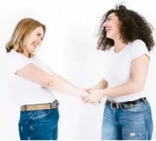 Dos jóvenes se saludan tomándose ambas las manos, transmitiendo confianza.