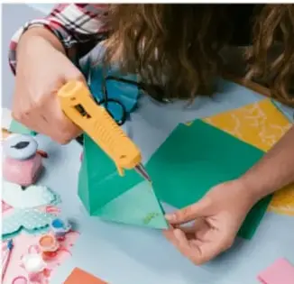 Persona cortando un papalote con tijeras y materiales sobre una mesa.
