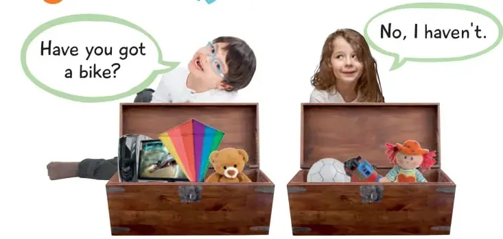 Dos niños con cajas de juguetes: uno pregunta 'Have you got a bike?' y la niña responde 'No, I haven't'. Dentro de las cajas hay un oso de peluche, un volantín, una muñeca y otros juguetes.