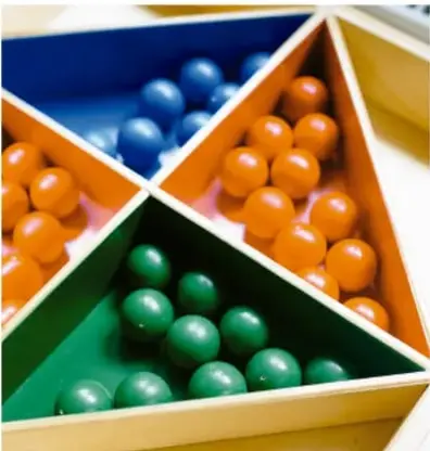 Caja triangular con compartimentos que contienen bolas de colores (azules, naranjas y verdes), usada como ejemplo visual de resultados que se excluyen entre sí.