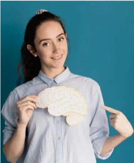 Fotografía de una joven estudiante de secundaria sosteniendo un modelo del cerebro humano, símbolo del pensamiento crítico y el juicio ético.