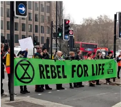 Manifestantes con pancarta verde 'REBEL FOR LIFE' de Extinction Rebellion.
