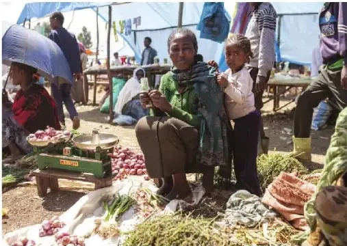 Personas afroecuatorianas en un mercado, junto a diversos productos y plantas.