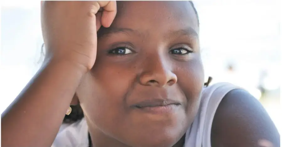 Primer plano de una niña afromexicana con la mano en la cabeza, mirando a la cámara.