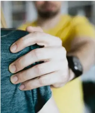 Fotografía de una mano apoyada con cuidado sobre el hombro de otra persona, como símbolo de protección y apoyo.