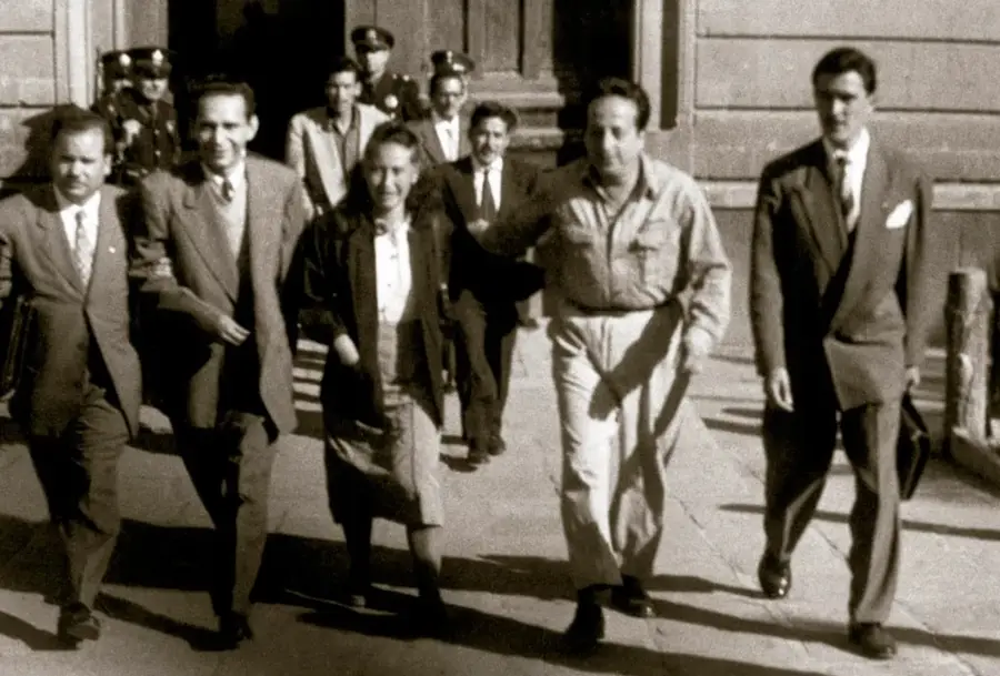 Fotografía en sepia del exlíder comunista Valentín Campa (centro, con camisa clara) caminando junto a otras personas, saliendo de la penitenciaria en enero de 1953; al fondo se ven agentes uniformados y la fachada del edificio.