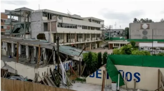 Fotografía del edificio del colegio Rébsamen parcialmente derruido, con estructura dañada y la leyenda 'DELITOS' en la barda.