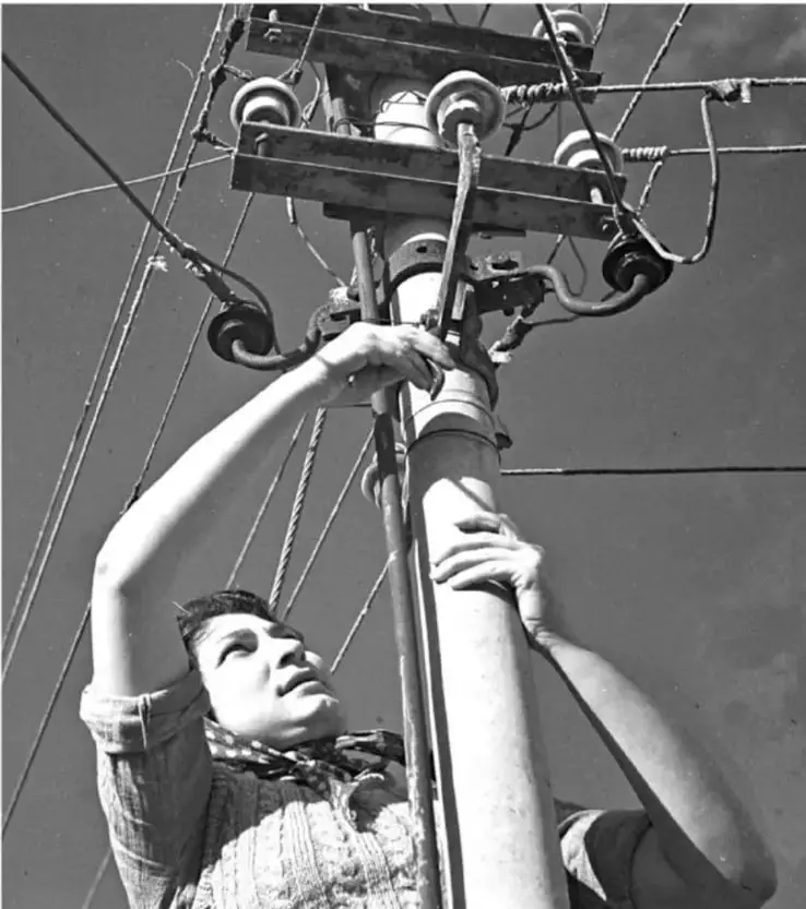 Fotografía en blanco y negro de una persona subida a un poste de luz, sosteniendo cables y herramientas, como ejemplo de esfuerzo y colaboración para lograr una mejora.