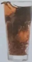 Vaso de gaseosa oscura con burbujas.