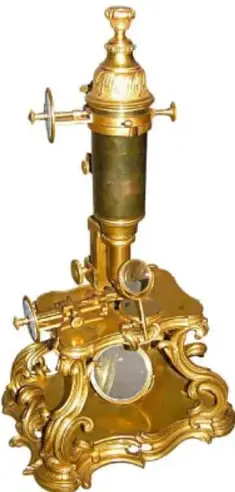Microscopio antiguo de latón ornamentado, con tubo y lentes.