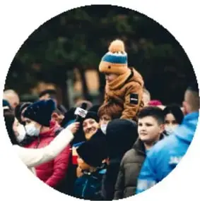 Fotografía de una familia en un evento multitudinario, niño en los hombros de un adulto