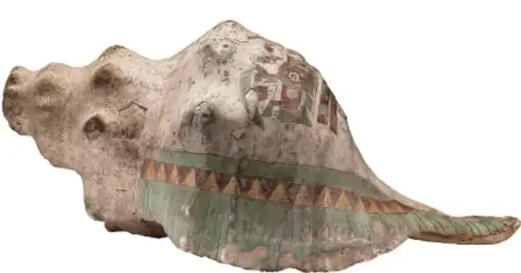Caracola marina grabada con figuras geométricas y líneas rojas y verdes, usada posiblemente como trompeta ritual.