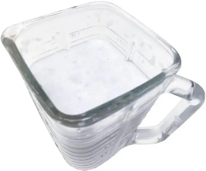 Vaso de licuadora con trozos de papel blanco remojando en agua.