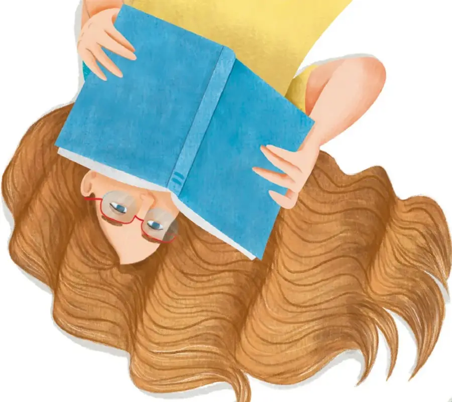 Niña con cabello largo y castaño, lentes rojos, leyendo un libro azul abierto sobre su cabeza.