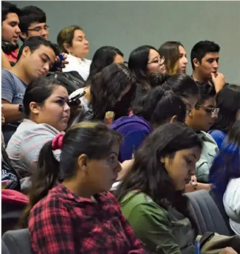 Fotografía de una joven con audífonos rojos frente a una laptop, participando en una videollamada con varias personas.