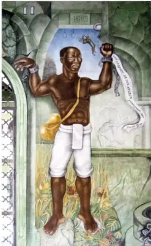 Retablo o escultura policromada de un hombre desnudo de pie con las manos alzadas y cadenas rotas colgando de las muñecas, enmarcado por un arco decorado.