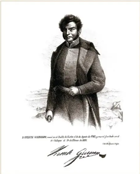 Litografía de Vicente Guerrero (L. Garcés, 1874, fotomecánico, Acervo INEHRM): retrato de cuerpo entero del militar insurgente con abrigo, sobre base con su firma.