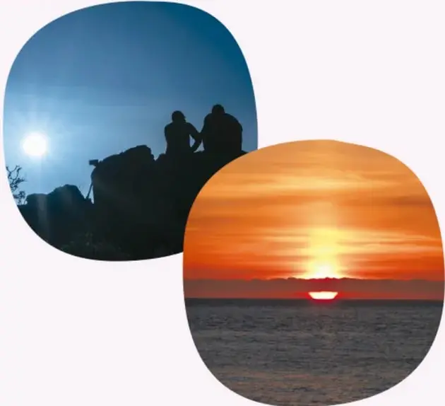 Fotografía de dos personas sentadas en la playa observando el sol bajo en el cielo.