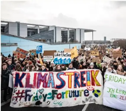 Marcha de jóvenes con pancartas que dicen KLIMASTREIK, #FridaysForFuture y 'Like the Sea'.