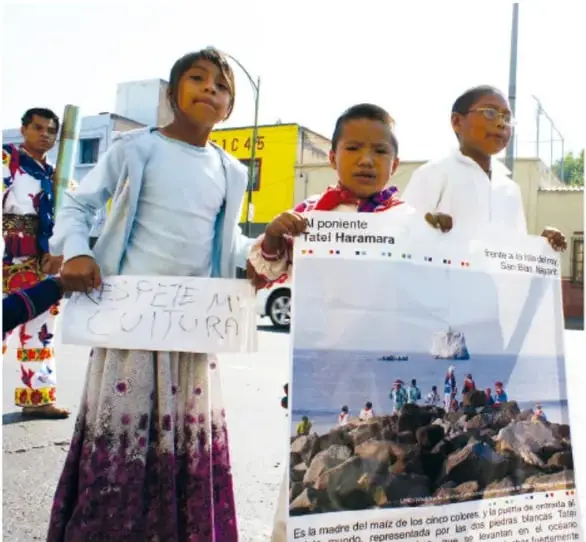 Niñas y niños sostienen carteles con mensajes como "RESPETE MI CULTURA" y "Al poniente Tatai Haramara".