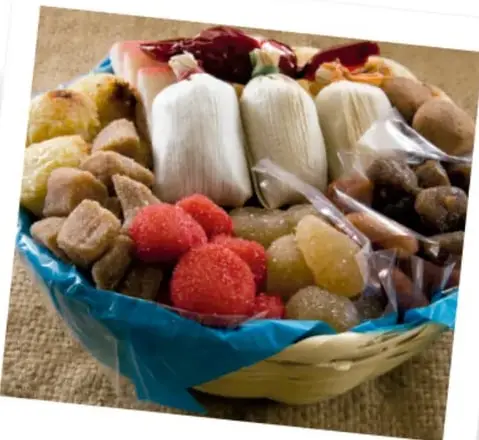 Fotografía de una canasta con dulces tradicionales mexicanos, como tamarindo, cocadas y frutas cristalizadas.