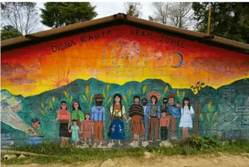 Mural comunitario con la frase 'Digna rabia' y figuras de personas indígenas frente a un paisaje.
