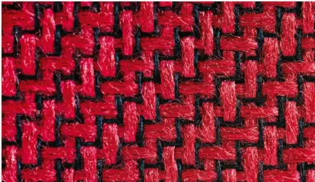 Fotografía de un tejido de palma (o fibra) con patrón geométrico de cruces rojas sobre fondo negro, ejemplo de patrón teselado en artesanía.