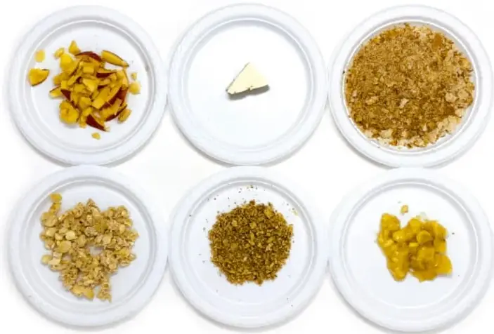 Seis platos desechables con alimentos antes de agregar el yodo: rodajas de manzana, trozo de queso, nueces machacadas, pan, camote o elote y plátano.