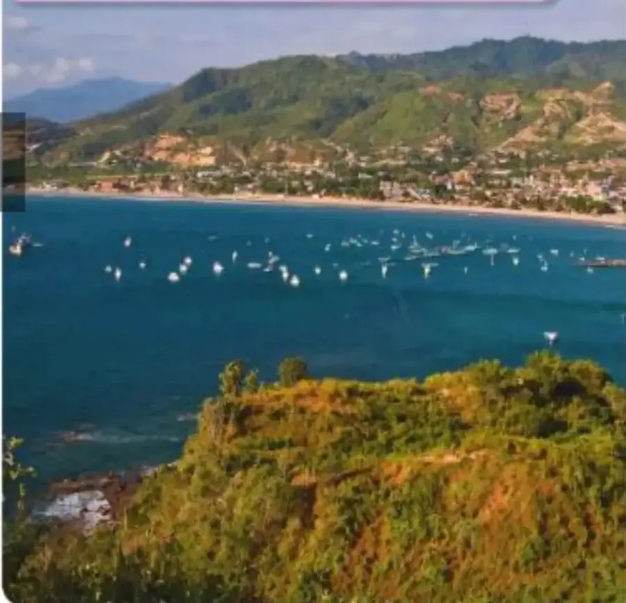 Fotografía de Puerto López, un lugar de vacaciones en la costa ecuatoriana, con el mar, embarcaciones, vegetación y montañas.