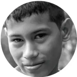 Fotografía en blanco y negro de un niño indígena sonriendo, mirando a la cámara.