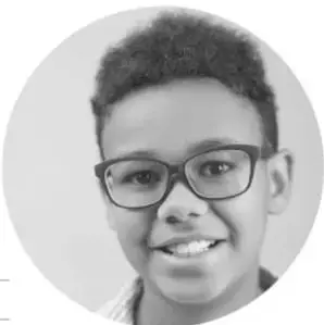 Fotografía circular en blanco y negro de un niño sonriente con lentes de armazón grueso.