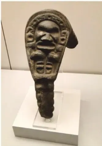 Escultura taína antropomorfa de piedra o madera, con rasgos faciales marcados, sobre pedestal en museo.