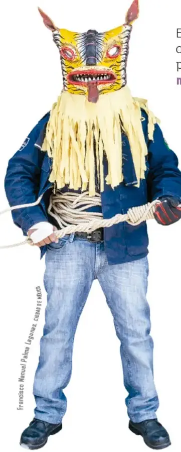 Persona de pie con cuerpo humano (chaqueta azul, jeans) que lleva una máscara de tigre o jaguar con lengua roja afuera y flecos de piel o ixtle amarillo; sostiene una cuerda. Crédito vertical: Francisco Manuel Palma Legaspi, costa de Michoacán.