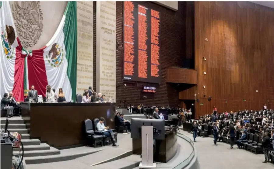 Fotografía del salón de sesiones del Congreso de la Unión en México, con la bandera nacional al fondo, diputados en sus curules, una pantalla electrónica de votación y una mesa directiva.